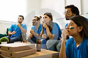 Hispanic friends looking worried while watching the soccer world cup