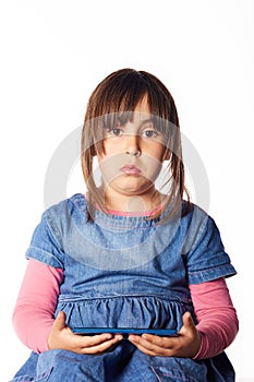 Hispanic girl of 5 years looking at camera with an surprise gesture and mobilephone in hands. white background and large copyspace