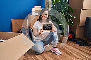 Hispanic girl with down syndrome sitting on the floor at new home winking looking at the camera with sexy expression, cheerful and
