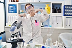 Hispanic girl with down syndrome working at scientist laboratory smiling cheerful showing and pointing with fingers teeth and