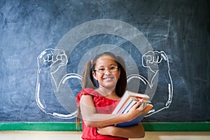 Hispanic Girl Holding Books In Classroom And Smiling