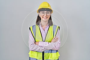 Hispanic girl wearing builder uniform and hardhat happy face smiling with crossed arms looking at the camera