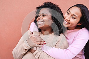 Hispanic girls laughing together and hugging each other outdoor - Focus on left woman face