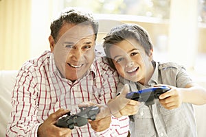 Hispanic Grandfather And Grandson Playing Video Game At Home