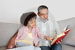 Hispanic grandpa and grandson kid enjoying book reading at home