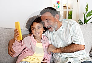 Hispanic Grandpa And Grandson Using Cellphone Together At Home