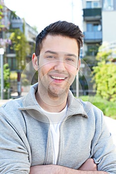 Hispanic guy in a grey jacket with crossed arms outside