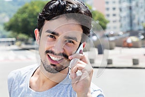 Hispanic guy in a grey shirt at phone in city