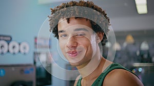 Hispanic guy posing store inside closeup. Curly smiling youngster resting cafe