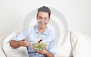 Hispanic guy on a sofa loves fresh salad