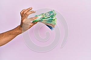 Hispanic hand holding south africa rands banknotes over isolated pink background photo