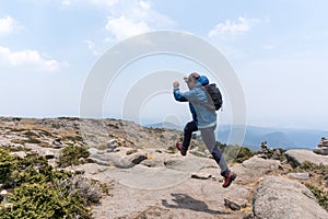 Hispanic hiker jumping up on mount Tlaloc under a cloudy sky in Mexico