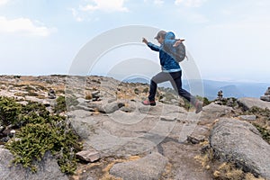 A Hispanic hiker jumping up on mount Tlaloc under a cloudy sky in Mexico