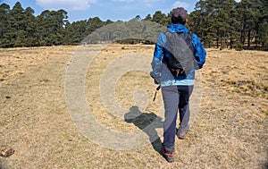 A Hispanic hiker walking on a field near mount Tlaloc in Mexico