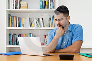 Hispanic hipster man stay at home and work with concentration at computer
