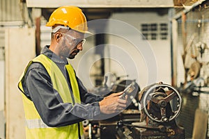 Hispanic Latin Indian male professional tecnician worker working with steel precision milling machine in lathe metal factory photo