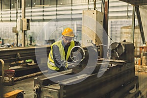 Hispanic Latin Indian male professional tecnician worker working with steel precision milling machine in lathe metal factory photo