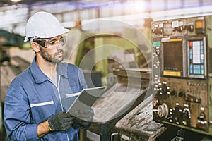 Hispanic latin indian male worker working control operate lathe CNC machine in heavy metal steel factory