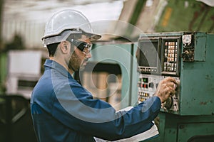 Hispanic latin indian male worker working control operate lathe CNC machine in heavy metal steel factory