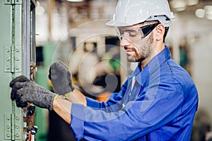 Hispanic latin labor worker hard working with safety glasses and helmet with heavy metal machine in factory industry