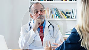 Hispanic male doctor listening to female patient