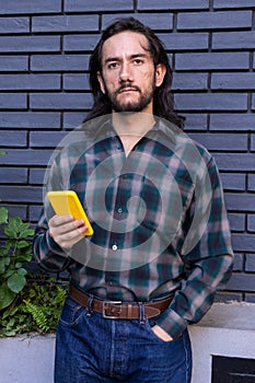 Hispanic male in his twenties holding a smartphone in his right hand