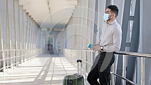 Hispanic male passenger business man wears formal clothes and face protective medical mask holds passport boarding pass