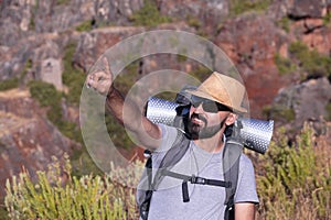 Hispanic male trekker with sunglasses smiling and pointing out of the frame