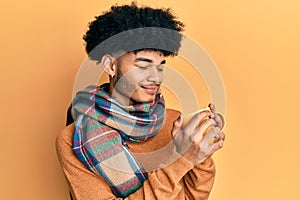 Hispanic man with afro hair smelling coffee aroma relaxed with eyes closed