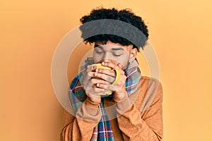 Hispanic man with afro hair smelling coffee aroma relaxed with eyes closed