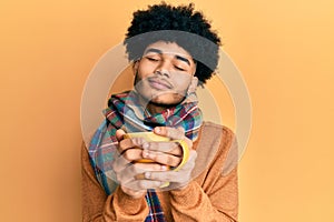 Hispanic man with afro hair smelling coffee aroma relaxed with eyes closed