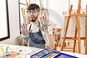 Hispanic man with beard at art studio afraid and terrified with fear expression stop gesture with hands, shouting in shock