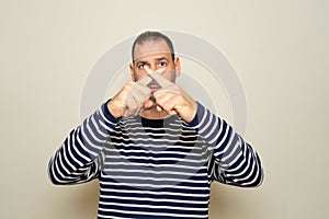 Hispanic man with beard in his 40s wearing a striped sweater standing over isolated beige background.Rejection