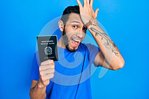 Hispanic man with beard holding italy passport surprised with hand on head for mistake, remember error