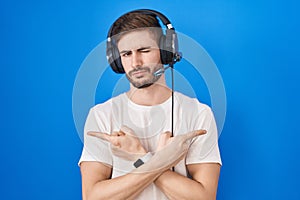 Hispanic man with beard listening to music wearing headphones pointing to both sides with fingers, different direction disagree