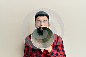 Hispanic man with beard screaming with vintage megaphone