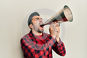 Hispanic man with beard screaming with vintage megaphone