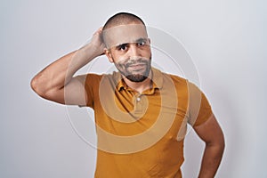 Hispanic man with beard standing over white background confuse and wondering about question