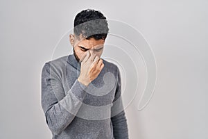 Hispanic man with beard standing over white background tired rubbing nose and eyes feeling fatigue and headache