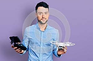 Hispanic man with beard using drone with remote control relaxed with serious expression on face