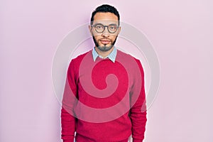 Hispanic man with beard wearing business shirt and glasses relaxed with serious expression on face