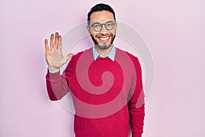 Hispanic man with beard wearing business shirt and glasses showing and pointing up with fingers number five while smiling