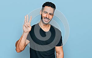 Hispanic man with beard wearing casual black t shirt showing and pointing up with fingers number three while smiling confident and