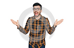 Hispanic man with beard wearing casual clothes and glasses celebrating victory with happy smile and winner expression with raised