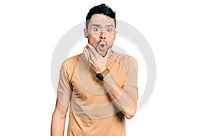 Hispanic man with beard wearing casual t shirt looking fascinated with disbelief, surprise and amazed expression with hands on