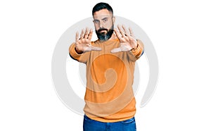 Hispanic man with beard wearing casual winter sweater doing frame using hands palms and fingers, camera perspective