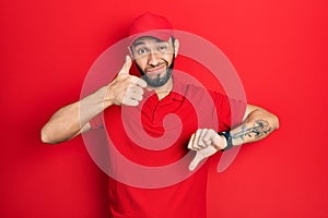 Hispanic man with beard wearing delivery uniform and cap doing thumbs up and down, disagreement and agreement expression