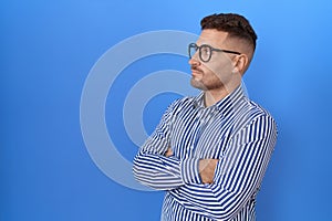 Hispanic man with beard wearing glasses looking to the side with arms crossed convinced and confident