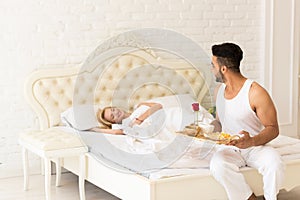 Hispanic Man Bring Breakfast To Sleeping Woman In Morning Tray With Red Rose Flower, Young Couple