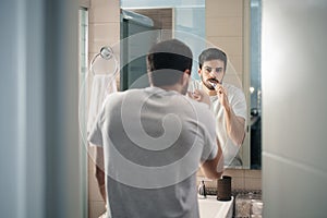 Hispanic man brushing teeth in bathroom at morning